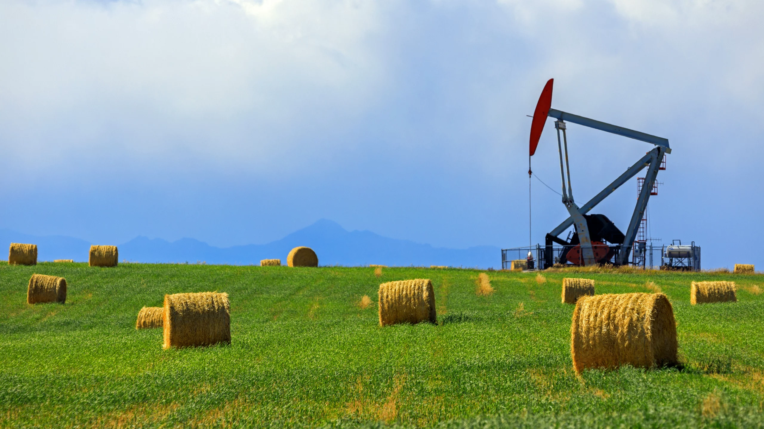 Pumpjack pumping for crude oil a field of hay bales